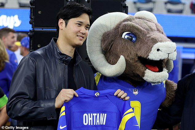 Shohei Ohtani holds up a Rams shirt as he steps