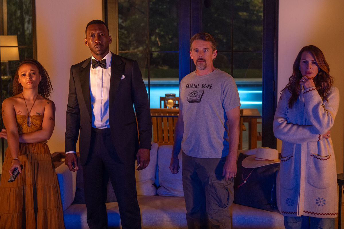 Myha'la, Mahershala Ali, Ethan Hawke and Julia Roberts stand next to each other and stare worriedly at a TV in the Netflix film Leave the World Behind