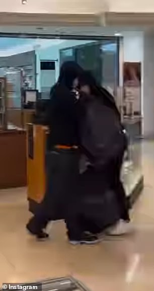 Two male robbers dressed in black used garbage bags to remove perfumes from the display cases