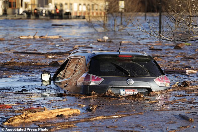 Travel in Maine was already in jeopardy after a massive storm Monday flooded rivers and knocked out power to hundreds of thousands of people.  Pictured: A car floats in a flooded parking lot at the Hathaway Creative Center along the Kennebec River in Waterville, Maine.