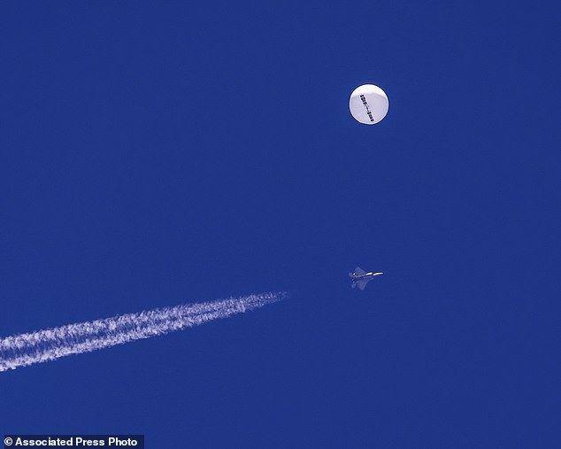 The spy balloon floats over the Atlantic Ocean just off the coast of South Carolina on Saturday, with a fighter jet and its contrail underneath