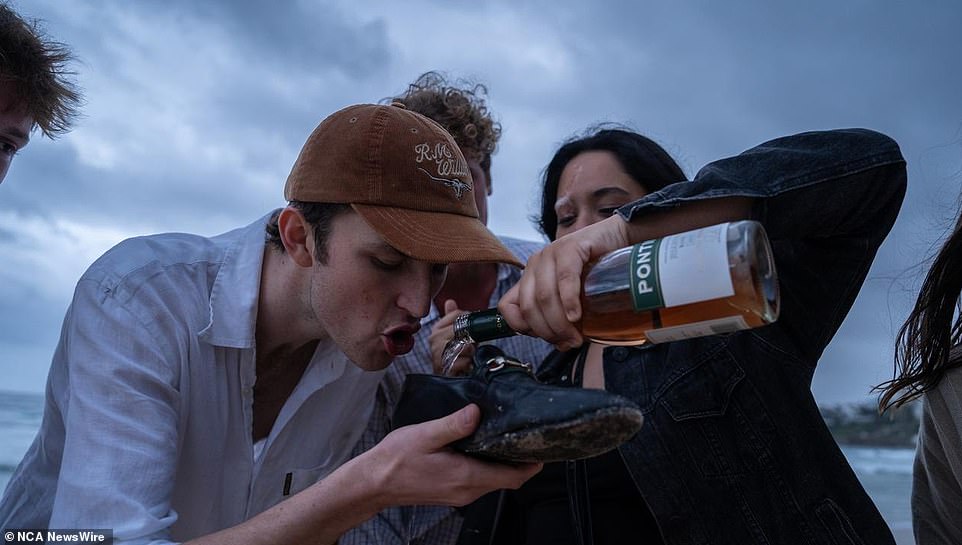 A Sydneysider takes a shoey on Bondi Beach and rings in the new year the Australian way