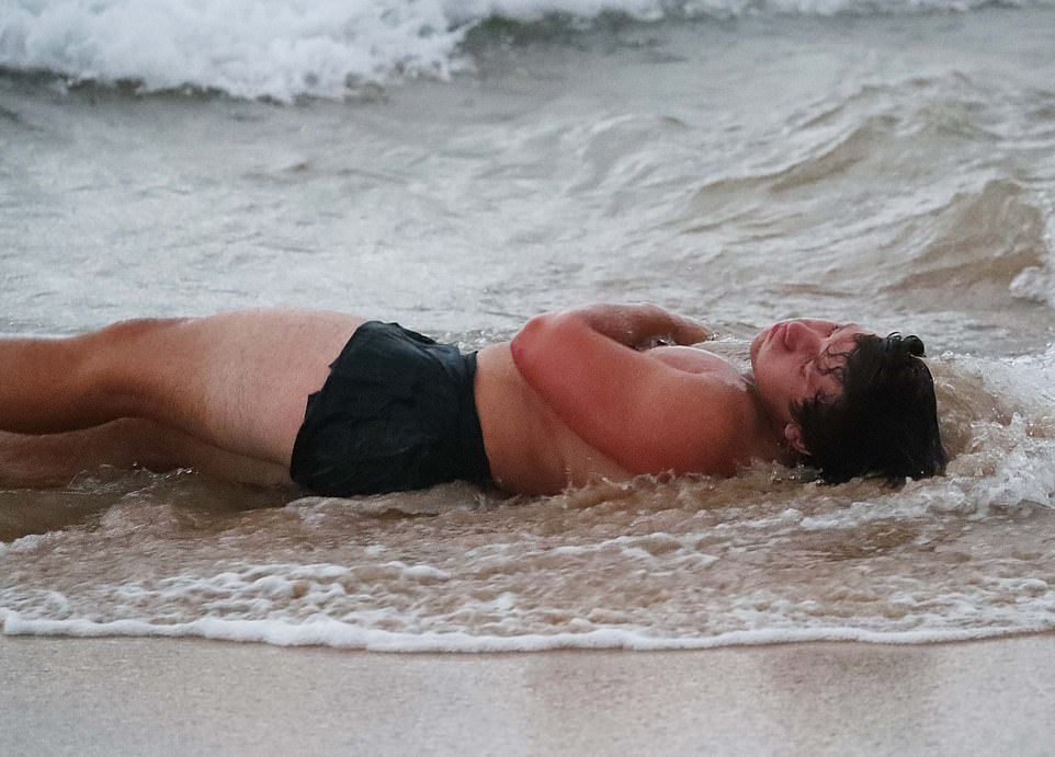 A reveler seen on Bondi Beach, lying in the surf, looking a little worse for wear after a night of partying