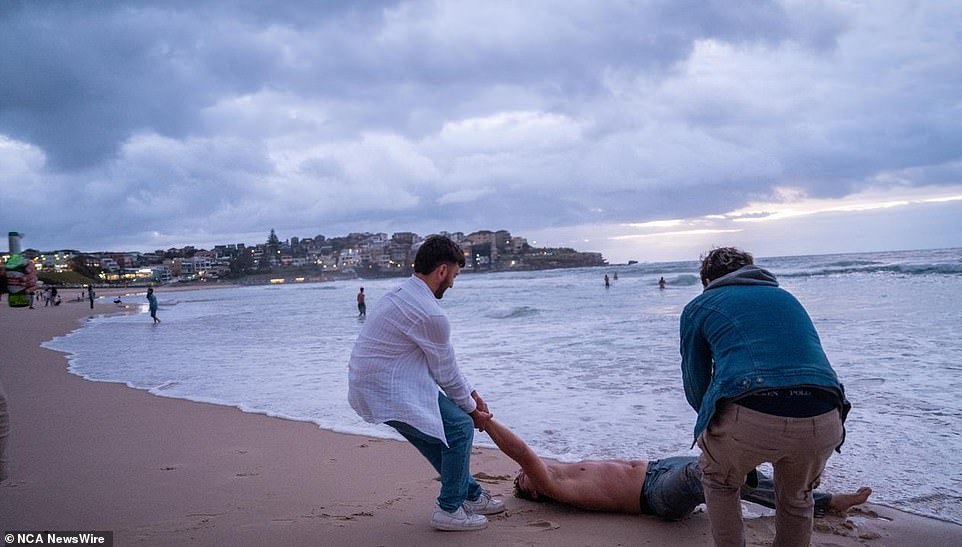 Two friends were seen dragging their friend across the sand and away from the water