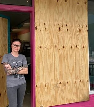 Sarah Swain next to the boarded up door after the second attack on her donut shop