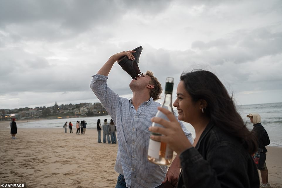 A Sydneysider takes a shoey on Bondi Beach and rings in the new year the Australian way