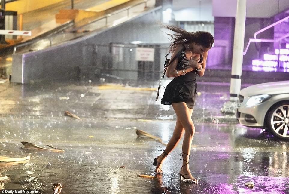 This artful shot, taken by a Daily Mail Australia photographer, shows a young woman in a party dress fleeing the wild rain