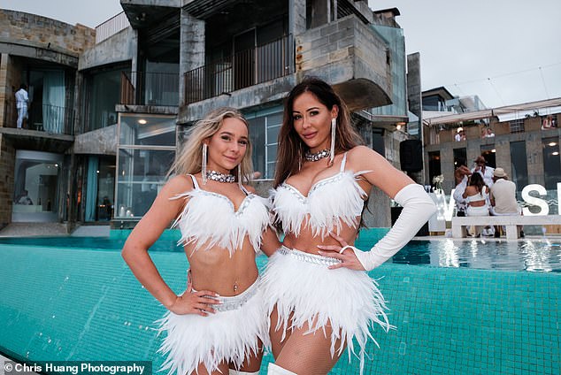 Two women wear matching sassy outfits by the pool of the expansive mansion