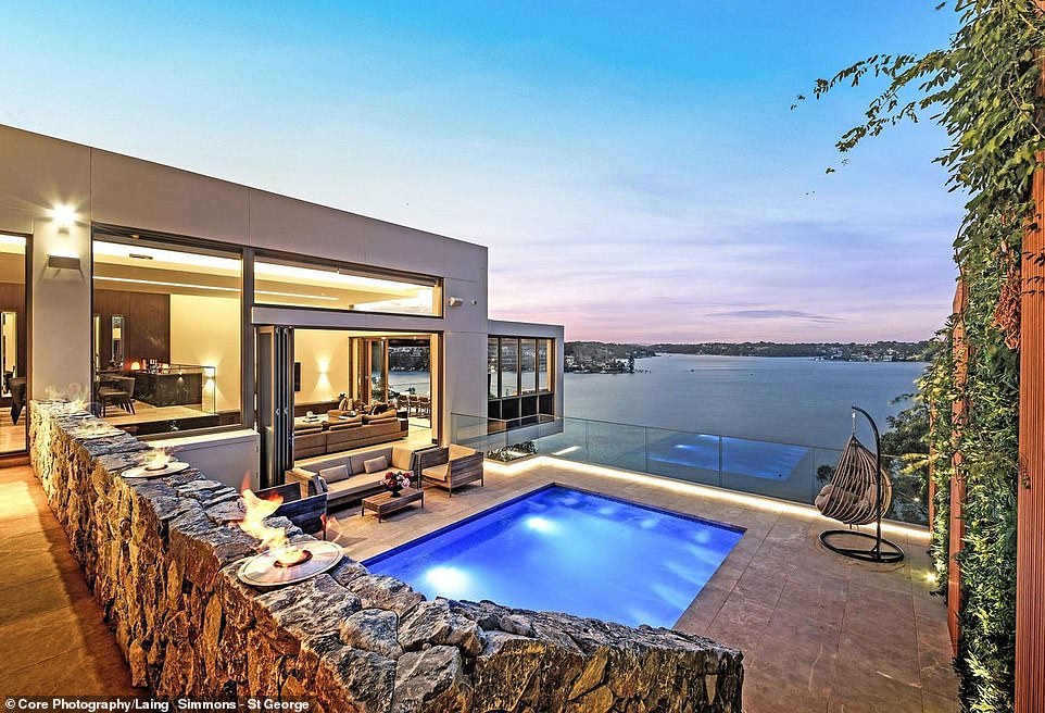 Flame torches sit atop a stone wall to add a touch of drama to the balcony off the living room, which features a mosaic heated pool, lush garden wall and conservatory