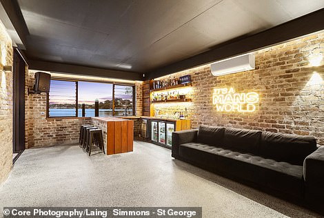 The man cave at the bottom of the block is a haven for men with a bar, surround sound speakers, exposed brick walls, neon signs and a fully stocked bar