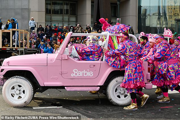 A group of parade participants walk behind a Barbie truck through the streets of Philadelphia during the annual Mummer's parade