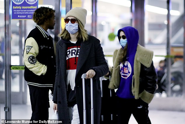 Casual: After her flight from London, the English model looked almost unrecognizable behind a face mask, sunglasses and a beige beanie over her signature golden locks