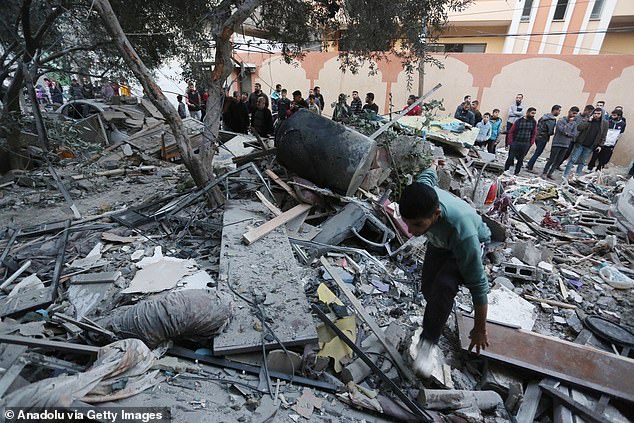 Palestinian man searches for valuables under the rubble of destroyed buildings after the Israeli attacks in Deir al-Balah, Gaza