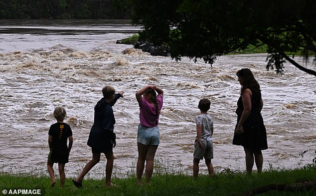 Residents look at the swollen Coomera River on the Gold Coast on Monday