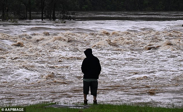 A Queensland resident observes the raging waters on the Coomera River on Monday