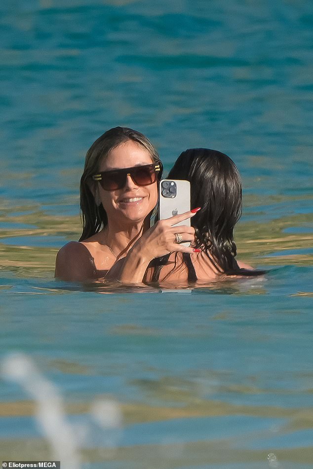 She had gone into the water with Tom, as the lovebirds cuddled and kissed while she continued to hold up her phone