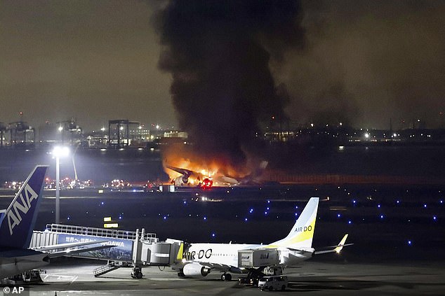 Smoke billows from the JAL plane after it landed on the tarmac outside Haneda Airport on January 2, 2024