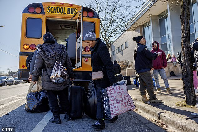 22-year-old Maria Silva (center), from Venezuela, carries her belongings to a bus outside the 6th District police station before being taken to a shelter along with other migrants staying at the station on Wednesday, December 13, 2023 .  in Chicago