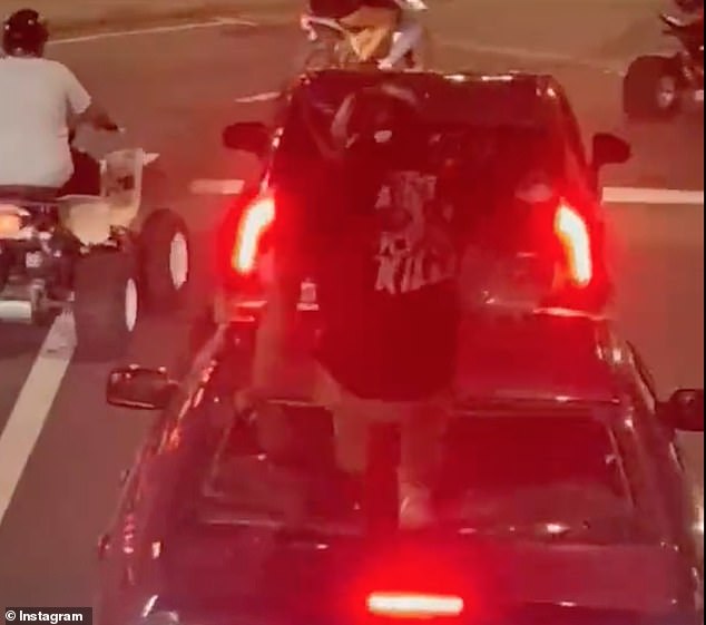 The motorcyclist smashes completely through the rear window of the car with both feet