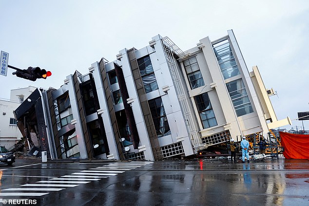 People stand near a collapsed building in the aftermath of an earthquake in Wajima, Japan, January 3