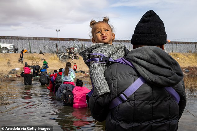 A migrant man crosses the Rio Grande with his child in the air to avoid getting wet as hundreds of migrants try to reach the U.S. border to seek humanitarian asylum in Ciudad Juarez, Mexico, on Jan. 2.