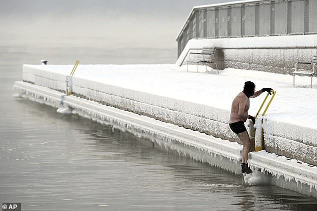 FINLAND: A man climbs out of the icy sea to the pier in southern Helsinki, January 2.  In Finland, the weather is forecast to remain cold across the country with temperatures down to minus 35 C in the north, at least until Sunday