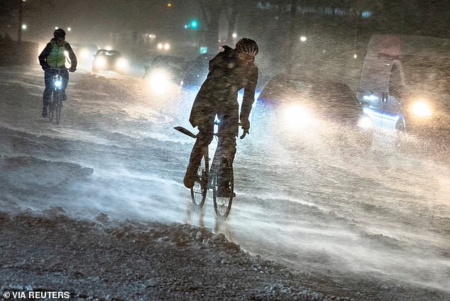 People cycle amid heavy snowfall in Aalborg, Denmark, January 3