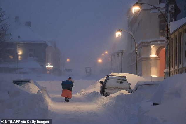 Icicles hang from lampposts as a woman makes her way through a snowstorm in Kristiansand, southern Norway, on January 3