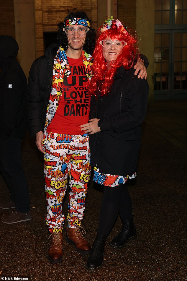 One man wears a 'stand up if you love the darts t-shirt' as he stands next to his friend