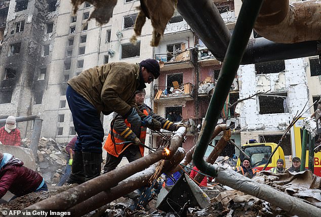 Utility workers repair water pipes outside a high-rise building destroyed by a Russian missile attack in central Kiev on January 3, 2024