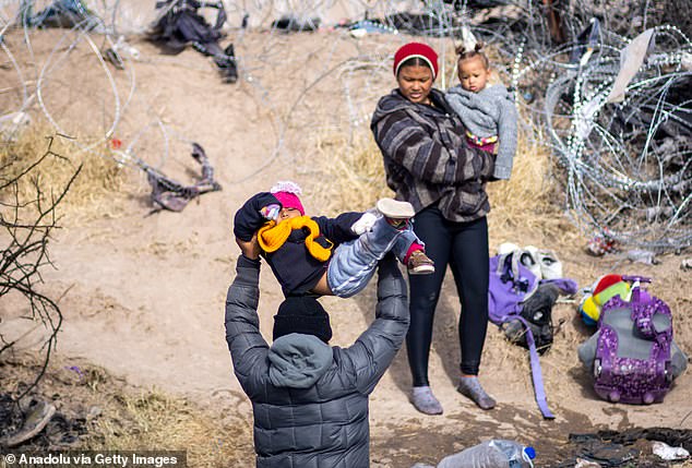 A migrant man crosses the Rio Grande with his child in the air to avoid getting wet on January 2, 2024