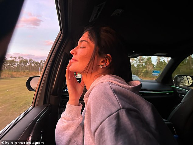 Kylie smiled with her eyes closed as she posed for a new photo near an open window in a car