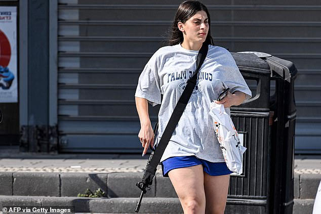 The young woman, wearing a baggy gray T-shirt, dark blue shorts and flip-flops, was seen carrying a bag of cargo to her car with the gun slung over her shoulder.