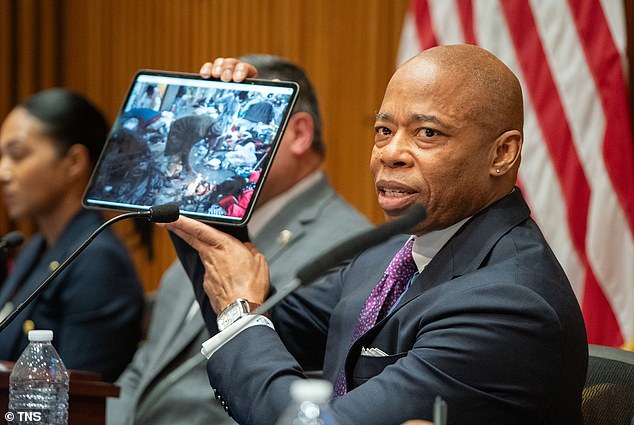 Adams is seen holding the photo of the homeless camp on Wednesday as crime statistics in his city are slightly lower