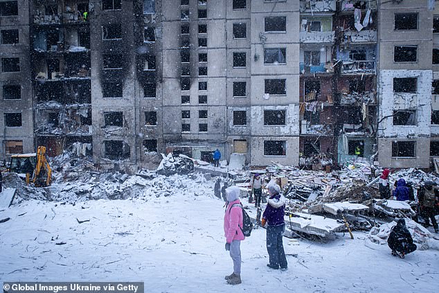 People stand in the courtyard of a residential apartment building damaged after a Russian missile attack on Kiev on January 2, 2024