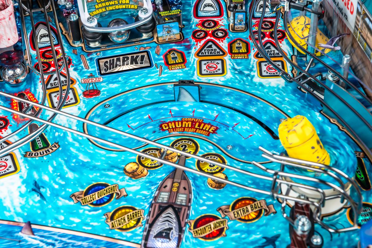 A close-up photo of the playing field of the pinball machine Jaws, focused on the “Chum Line” area with a fin-shaped moving target