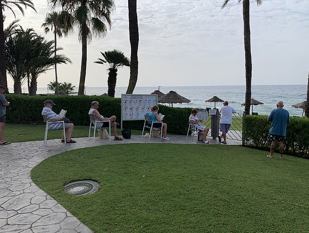 People queue for the sun loungers at Hotel Estival Torrequebrada near Malaga.  Many brought chairs and a good book as they waited nearly two hours for the beach and pool to open