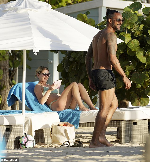 The couple appeared to be in good spirits as they smiled and laughed together while relaxing on the beach