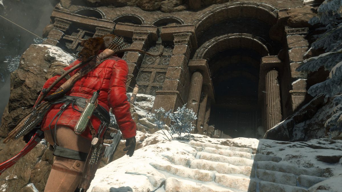 Lara Croft in a red winter coat walks up the snowy steps of a temple in Rise of the Tomb Raider.