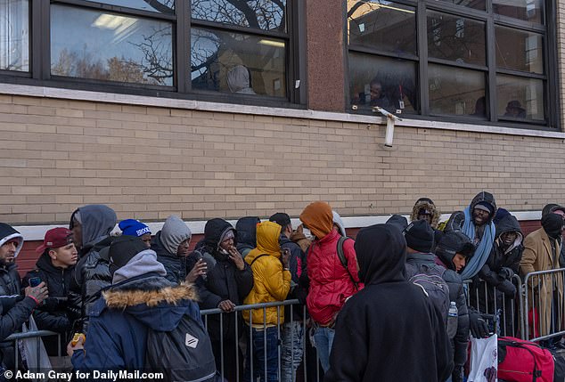Swarms of migrants waited all day Friday outside the former St. Brigid Catholic School in subzero temperatures, without blankets or warm clothing