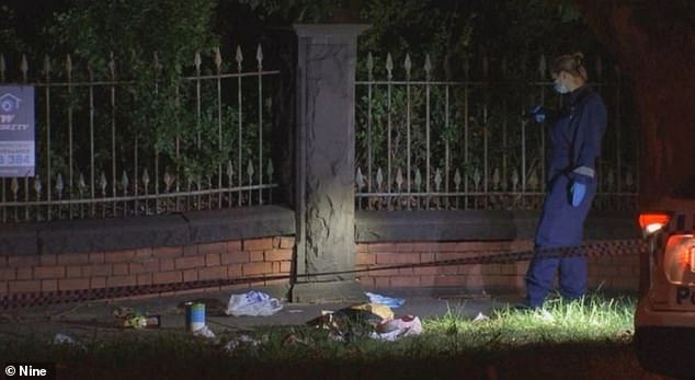 A woman is fighting for her life after she and the man she was with were stabbed while walking along Dandenong Rd in St Kilda East.  The photo shows a police officer looking for evidence