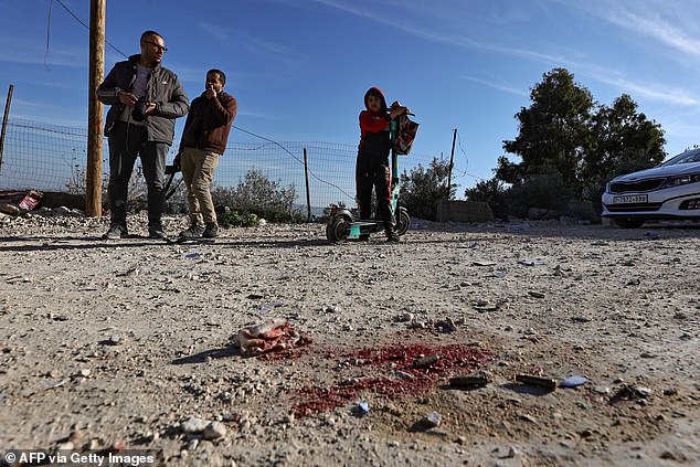 People look at a bloodstain near the site where an explosive device killed an Israeli officer during an Israeli raid on Jenin in the occupied West Bank