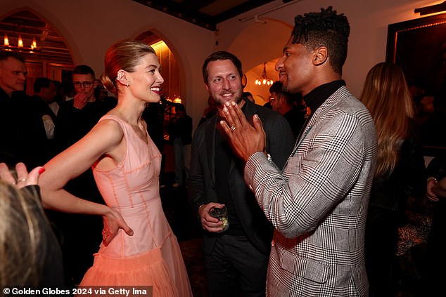 The actress added a pop of color to the peach dress and wore a pop of bright pink lipstick (pictured chatting with Matthew Heineman and Jon Batiste)