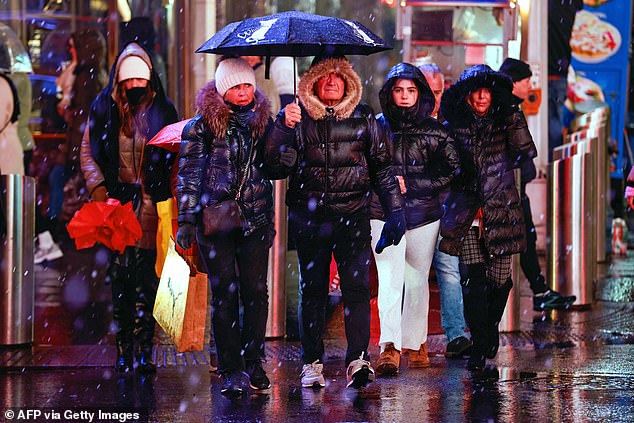 People walk through a wintry mix in Times Square on Saturday.  Central Park reported 0.5 inches of snowfall