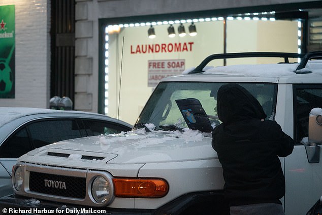 A person scrapes snow from a car in Stamford, Connecticut on Sunday