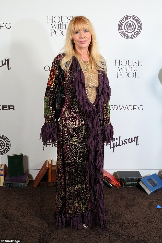 Rosanna went for a Steve Nicks look with a hippie-chic coat in gold, purple and maroon with fringes along the collar and sleeves.  Underneath was a gold top that matched her earrings, while she added a green peace sign necklace