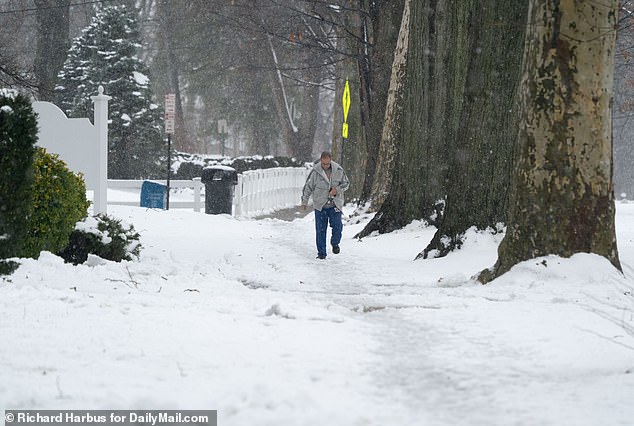 A man walks through the snow on Sunday in White Plains, New York, as snow hits the tri-state area