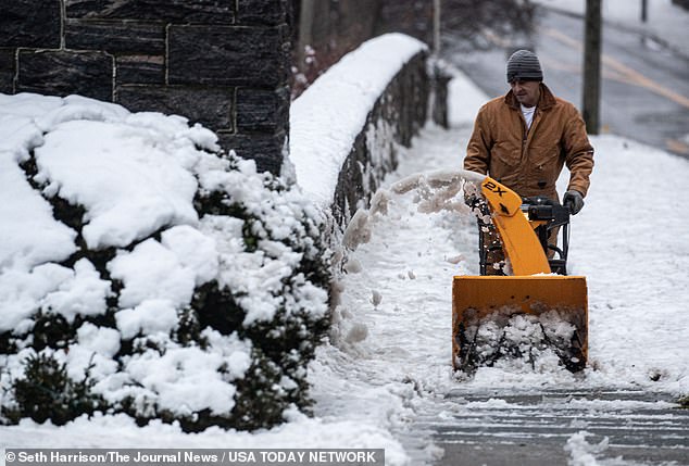 A man clears snow from the sidewalk in Tarrytown, New York, with a snow plow on Sunday