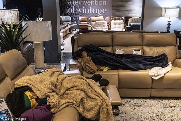 People sleep on couches as they take shelter inside the Gallery Furniture store, which opened its doors and turned it into a warming station after winter weather caused power outages in Houston on Feb. 18