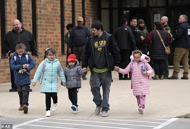 Children hold hands with a man wearing an Iowa sweatshirt as they are reunited after the shooting